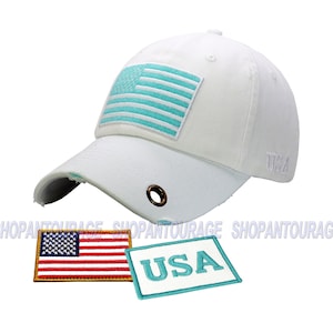 May include: White baseball cap with a distressed brim and a turquoise American flag patch on the front. The cap also has a small turquoise "USA" patch and the word "USA" embroidered on the side.