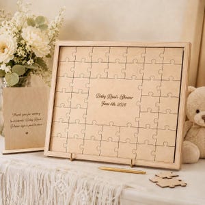 Könnte beinhalten: Ein hölzernes Puzzle-Gästebuch mit einem hellbraunen Rahmen und einem hellbraunen Puzzle. Der Text "Baby Rossi's Shower June 6th, 2026" ist auf dem Puzzle aufgedruckt. Ein kleineres Holzschild lautet: "Vielen Dank für Ihr Kommen, um Baby Rossi zu feiern! Bitte unterschreiben Sie ein Puzzleteil!"
