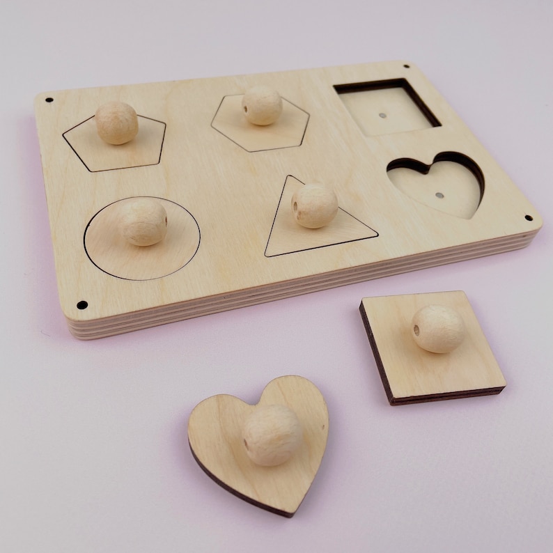 Puede incluir: Juguete de madera para clasificar formas con seis formas diferentes: c&iacute;rculo, cuadrado, coraz&oacute;n, tri&aacute;ngulo, pent&aacute;gono y hex&aacute;gono. Cada forma tiene una perilla de madera correspondiente para encajar en el recorte.