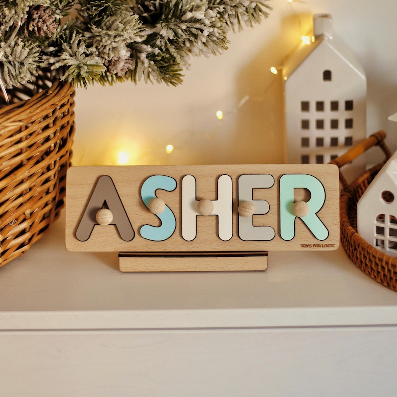 May include: A wooden name puzzle with the name "ASHER" spelled out in colorful letters. The puzzle is on a wooden stand and has small wooden knobs for each letter.
