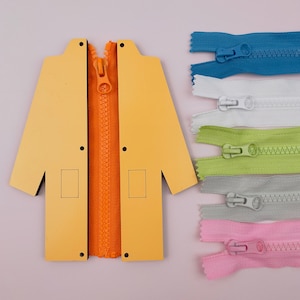 May include: A yellow wooden coat with a zipper opening. There are five different coloured zippers in the image, including blue, white, green, grey, and pink.