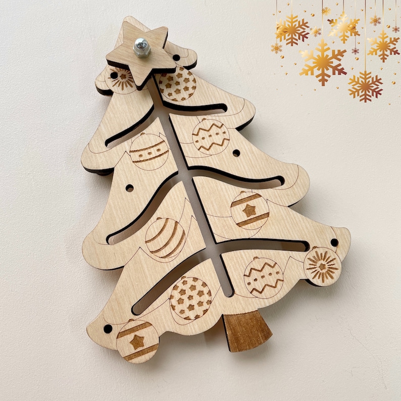 Puede incluir: Un adorno de &aacute;rbol de Navidad de madera con una estrella en la parte superior y recortes para adornos. El adorno es de color marr&oacute;n claro y tiene un acabado de madera natural.