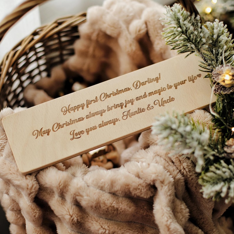 May include: A wooden plaque with a personalized message for a first Christmas. The message reads "Happy first Christmas, Darling! May Christmas always bring joy and magic to your life Love you always, Auntie & Uncle".