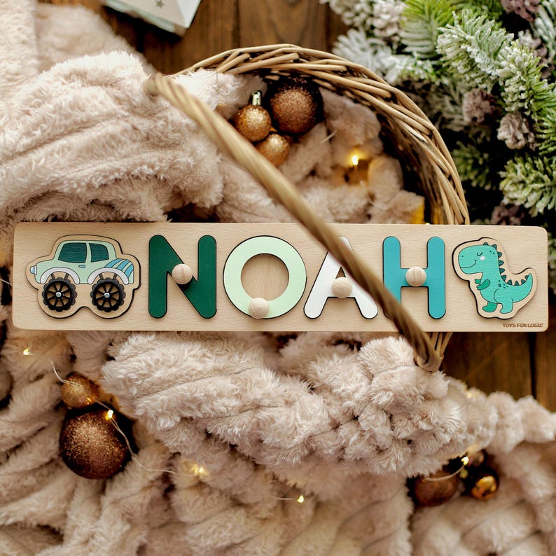 May include: A wooden name puzzle with the name "NOAH" spelled out in colorful letters. The puzzle pieces are shaped like a car, a dinosaur, and the letters of the name. The puzzle is on a wooden background.