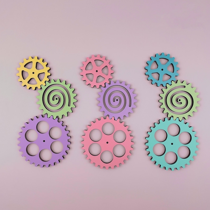 May include: A set of nine colorful wooden gears in various shapes and sizes. The gears are painted in pastel shades of yellow, green, blue, pink, and purple.
