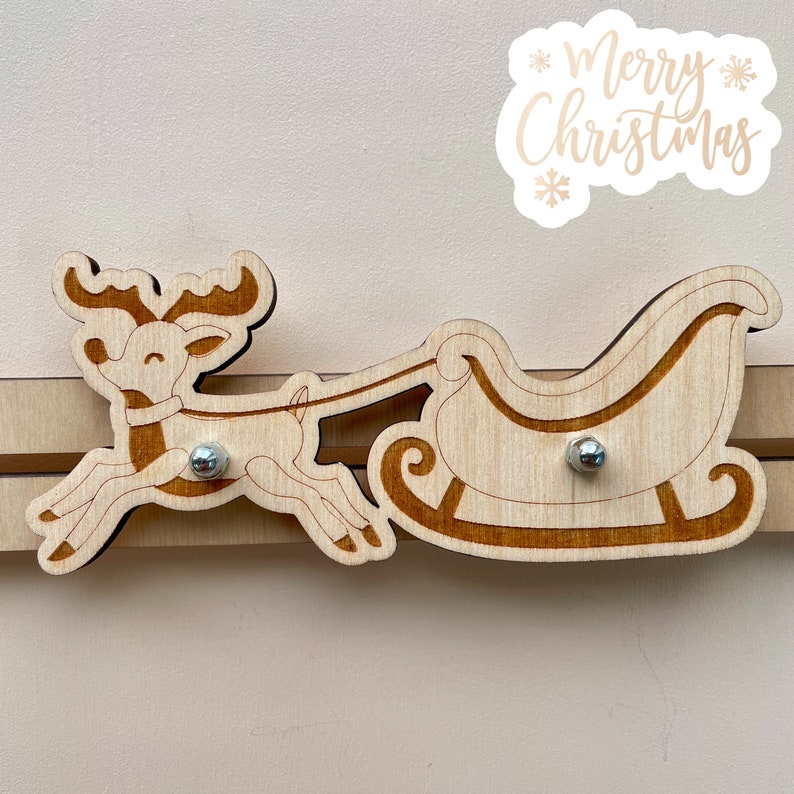 Puede incluir: Renos de madera tirando de un trineo con las palabras "Feliz Navidad" sobre un fondo blanco.