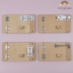 Puede incluir: Cuatro paneles de madera con diferentes tipos de pestillos y bisagras. Cada panel tiene una pequeña perilla de madera. Los paneles están dispuestos en una cuadrícula de 2x2. El texto "TOYS FOR LOGIC Kids Future" es visible en la esquina superior derecha.