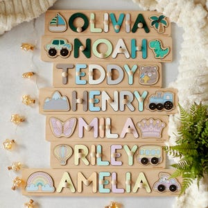 May include: Seven wooden puzzle pieces with names spelled out in colorful letters. Each piece has a different illustration, including a sailboat, car, bear, mountain, butterfly, hot air balloon, and unicorn.
