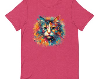 May include: A short-sleeved, pink t-shirt featuring a colorful, artistic rendering of a cat's face. The cat's fur is depicted with a mix of blue, orange, yellow, and green hues, creating a vibrant and eye-catching design. The cat has blue eyes.