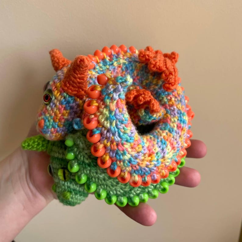 Two finished sensory dragons curled into coils and resting one on top of the other inside a cupped hand, showing their flexible, nesting shape.