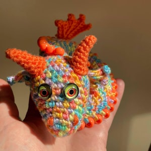 Profile view of an orange dragon’s head, clearly showing the ear, horn, and the first few beads of the crest, with soft lighting.