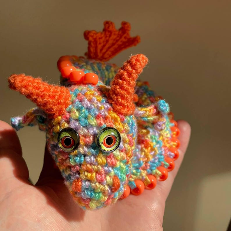 Profile view of an orange dragon’s head, clearly showing the ear, horn, and the first few beads of the crest, with soft lighting.
