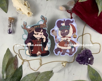 May include: Two illustrated stickers featuring a winter-themed deer and a bull. The deer is wearing a red and brown outfit with a crown of leaves and holding a staff. The bull is wearing a red and white outfit with a wreath of holly and holding a broom. Both stickers have a blue background with snowflakes.