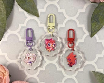May include: Three clear plastic keychains with different animal characters. The keychains are attached to metal rings with purple, red, and yellow accents. The characters are a white owl with pink accents, a red fox with yellow accents, and a white bear with pink accents.