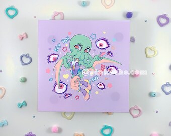 May include: A purple background with a green cartoon character with tentacles and wings. The character is surrounded by colorful eyes and stars. The text "Say You Love Me" is written in white on the background.