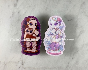 May include: Two illustrated stickers featuring anthropomorphic reptile characters. The sticker on the left features a brown reptile wearing a red and black outfit with a purple background. The sticker on the right features a white reptile wearing a purple and blue outfit with a pink background. The text "@pinkaske.com" is visible on the stickers.