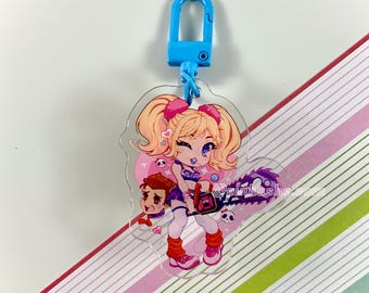 May include: A clear acrylic keychain featuring a cartoon girl with pink pigtails holding a chainsaw. She is wearing a purple and white outfit with a pink heart on her chest. The keychain has a blue metal clasp.