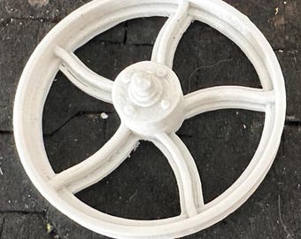 Puede incluir: Rueda de modelo de plástico blanco con cinco radios y un cubo central. La rueda está diseñada para parecer una rueda de automóvil vintage.