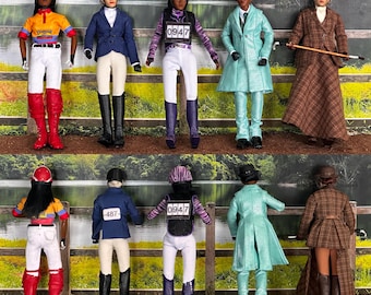 Puede incluir: Una colección de muñecas ecuestres vestidas con atuendos de equitación. Las muñecas visten varias prendas, incluyendo chaquetas, pantalones de montar y botas de montar. Algunas muñecas tienen cascos y llevan fustas. Las muñecas posan frente a una valla de madera y un fondo verde.