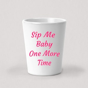 Peut inclure: Un verre à shot en céramique blanche avec le texte "Sip Me Baby One More Time" en lettres roses.