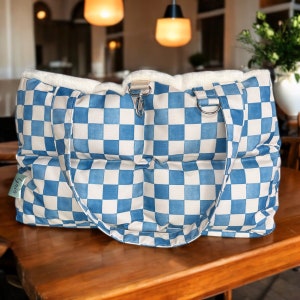May include: A blue and white checkered tote bag with a white sherpa lining and two handles. The bag is made of a quilted fabric and has a small tag that says "Linen".