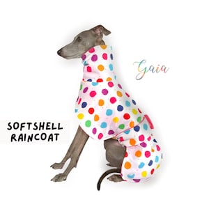 以下が含まれることがあります： グレーのイタリアングレイハウンドが、白、ピンク、レインボーのドット柄のソフトシェルレインコートを着ています。レインコートはピンクの襟とピンクのベルトが付いています。犬は座って左を見ています。画像の右上に「Gaia」という文字が虹色の文字で書かれています。画像の左下に「Softshell Raincoat」という文字が黒文字で書かれています。