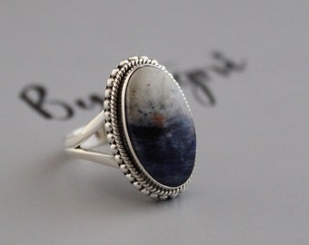 May include: A silver ring with a blue and white oval gemstone set in a beaded bezel.