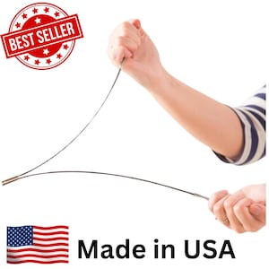 May include: A flexible, thin, dark-colored metal wire tool with metallic cylindrical end caps. The tool is held at both ends, showing its bendable nature. A red circular badge with white stars and the text BEST SELLER is visible, along with the text Made in USA.
