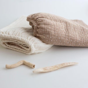 Peut inclure: Deux morceaux de tissu pliés, un blanc et un brun à pois blancs. Le tissu est doux et texturé.