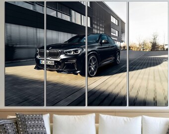 May include: A four-panel wall art print featuring a black SUV speeding down a wooden planked road. The car is the focal point, with a blurred background of a modern building and trees. The artwork is displayed above a white sofa with decorative pillows.
