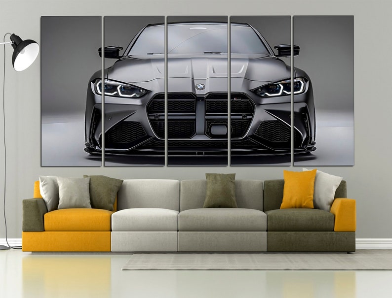 Puede incluir: Impresi&oacute;n en lienzo de un coche deportivo gris, visto de frente. El coche tiene detalles en negro y faros brillantes. La obra de arte se exhibe sobre un sof&aacute; moderno con cojines amarillos y grises.