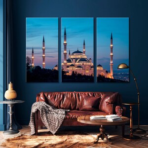 May include: A three-panel canvas print featuring a white mosque with minarets against a blue twilight sky. The mosque is illuminated with warm lights, creating a serene and peaceful atmosphere.