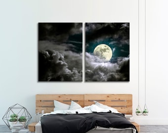 Puede incluir: Arte mural de dos paneles que representa una luna llena que emerge de nubes oscuras y dramáticas. La luna es de color amarillo brillante sobre un fondo turquesa. La obra de arte se exhibe sobre una estructura de cama de madera con un edredón negro.
