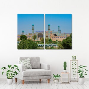 May include: Two-panel wall art featuring a detailed view of a mosque with intricate blue and gold tilework. The mosque has multiple minarets and is set against a clear blue sky. The artwork is displayed above a gray armchair with a decorative pillow, surrounded by potted plants.