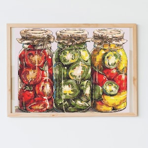 Pode incluir: Uma obra de arte emoldurada com três frascos de vidro cheios de vegetais em conserva. Os frascos contêm tomates vermelhos, jalapeños verdes e uma mistura de produtos amarelos e vermelhos. Cada frasco tem uma tampa rústica e é amarrado com barbante.
