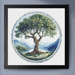May include: Framed artwork featuring a detailed cross-stitch design of a tree with a twisted trunk and lush green foliage. The tree is set within a circular frame, surrounded by a blue and white border, with a serene landscape backdrop.