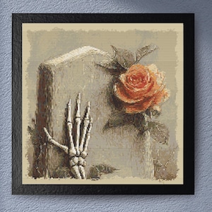 May include: Framed artwork featuring a skeleton hand reaching towards a peach-colored rose. The rose is in full bloom with green leaves. The background has a sepia tone, and the artwork is in a black frame.