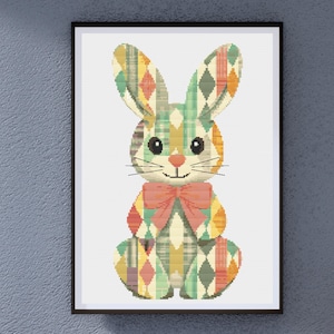 May include: A colorful geometric pattern bunny rabbit with a pink bow tie. The bunny is sitting on a white background.