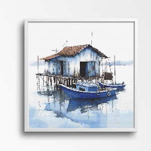 May include: A white wooden house on stilts over the water with two blue boats docked in front of it. The water is a light blue and the sky is a light gray.