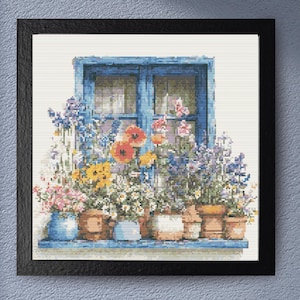 Könnte beinhalten: Ein gerahmtes Kreuzstich-Kunstwerk zeigt ein blaues Fenster mit Blumentöpfen. Der Fensterrahmen ist blau, und die Blumen umfassen rosa, gelbe und orangefarbene Blüten. Das Kunstwerk ist in einem schwarzen Rahmen gerahmt.