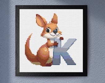 May include: Cross-stitch artwork of a cartoon kangaroo holding a large letter "K". The kangaroo is brown and tan with a white belly and blue accents. The letter "K" is blue and gray. The artwork is framed in a black frame.