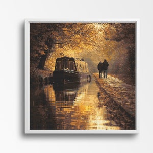 May include: Framed art print of a canal scene, featuring a boat and two figures on the bank. The artwork uses warm, golden hues, possibly depicting a sunset or autumn. The water reflects the boat and the surrounding trees, creating a tranquil atmosphere.