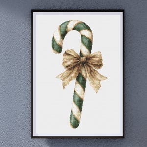 May include: A framed print featuring a watercolor illustration of a green and white striped candy cane with a large, gold-colored bow. The artwork is set against a white background, perfect for holiday decor.