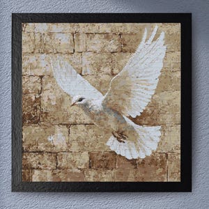 May include: A framed artwork featuring a white dove in flight against a textured brick wall background. The dove's wings are spread, and the artwork is encased in a black frame, creating a striking contrast.
