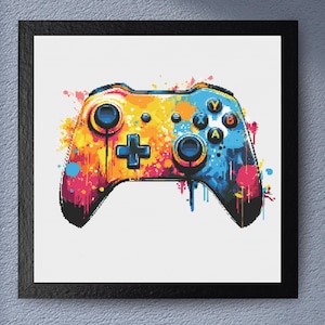 May include: A framed print featuring a colorful, pixelated image of a video game controller. The controller is painted with vibrant hues of orange, yellow, blue, and pink, with a splash art effect. The buttons and joysticks are clearly defined.
