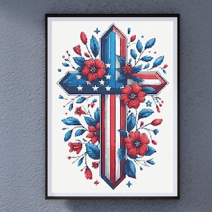 May include: Framed artwork featuring a cross design with patriotic colors and floral accents. The cross is adorned with red, white, and blue stripes and stars, surrounded by red flowers and blue leaves. The artwork is displayed in a black frame.