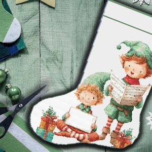 Puede incluir: Un calcetín navideño con una ilustración de dos elfos cantando villancicos. Los elfos visten trajes y sombreros verdes, uno de ellos sosteniendo un letrero en blanco. También se representan regalos y copos de nieve.