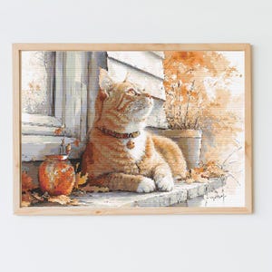 May include: A framed watercolor painting of a ginger cat with a bell collar, gazing upwards. The cat is resting on a stone ledge with autumn leaves. A small orange jar and potted plants are also visible, with a wooden frame.