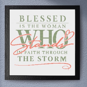 May include: A framed print with the text "BLESSED IS THE WOMAN WHO Stands IN FAITH THROUGH THE STORM." The text is in green and coral colors on a white background, framed in black. The artwork is displayed against a textured, light blue wall.