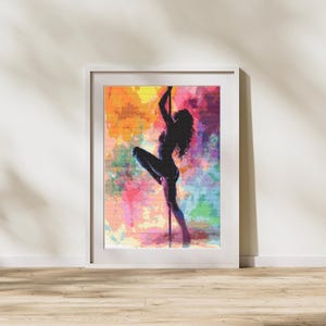May include: Framed artwork featuring a silhouette of a person pole dancing. The figure is set against a vibrant, colorful background with hues of orange, pink, purple, and blue. The artwork is displayed in a white frame.